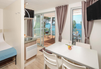 Indvendig udsigt fra Lanterna Home Seaside chalet med spisebord og terrasse udsigt til havet i Kroatien.