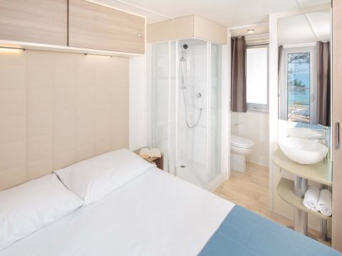 Helles, modernes Schlafzimmer mit Doppelbett, Dusche und Meerblick im Lanterna Home Seaside in Kroatien.