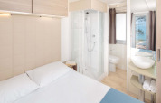 Helles, modernes Schlafzimmer mit Doppelbett, Dusche und Meerblick im Lanterna Home Seaside in Kroatien.