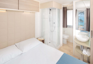 Helles, modernes Schlafzimmer mit Doppelbett, Dusche und Meerblick im Lanterna Home Seaside in Kroatien.