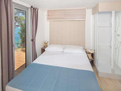Schlafzimmer im Lanterna Home Seaside Chalet im Valamar Camping Lanterna, mit Meerblick in Kroatien.