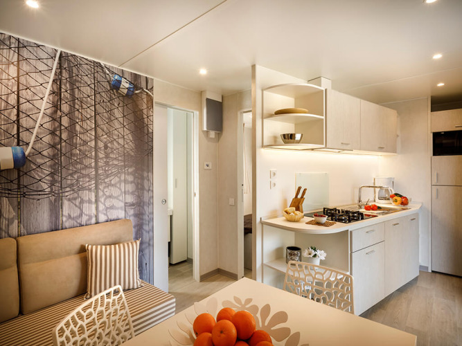 Licht glampingverblijf met moderne kitchenette, eethoek en gezellige zithoek in natuurlijke tinten.