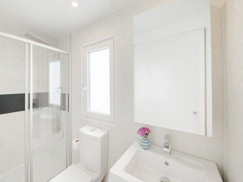 Bagno moderno in uno chalet con doccia, WC, lavandino e finestra al Valamar Camping Lanterna, Croazia.