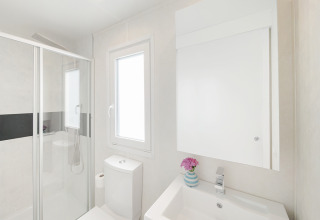 Bagno moderno in uno chalet con doccia, WC, lavandino e finestra al Valamar Camping Lanterna, Croazia.