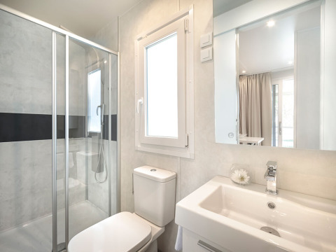 Bagno moderno in una sistemazione glamping con doccia, finestra, wc e lavabo con specchio.