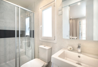 Bagno moderno in una sistemazione glamping con doccia, finestra, wc e lavabo con specchio.