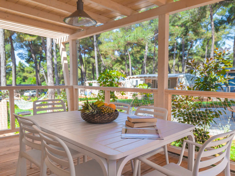 Terrazza in legno con tavolo da pranzo, sedie e cesta di frutta nel chalet Marine Home di Valamar Camping Lanterna, Croazia.