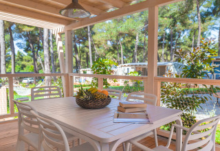 Terrazza in legno con tavolo da pranzo, sedie e cesta di frutta nel chalet Marine Home di Valamar Camping Lanterna, Croazia.