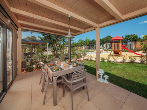 Udendørs spiseplads på en overdækket terrasse ved Mediterranean Garden Home i Valamar Camping Lanterna, Kroatien.