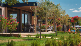 Blick auf ein modernes Mediterranean Garden Home Chalet mit Garten, Blumen und Terrasse an einem sonnigen Tag.
