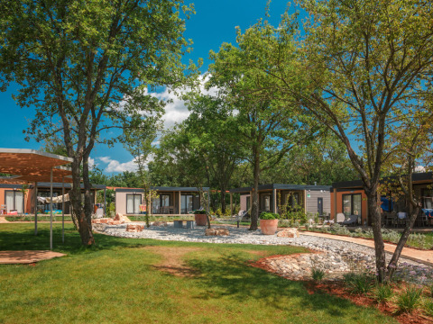 Udsigt over Mediterranean Garden Home chalet på Valamar Camping Lanterna i Kroatien, omgivet af grønne træer.