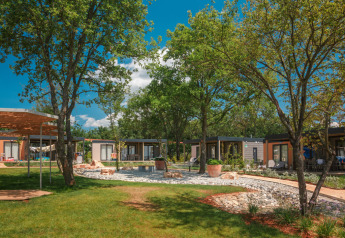 Udsigt over Mediterranean Garden Home chalet på Valamar Camping Lanterna i Kroatien, omgivet af grønne træer.