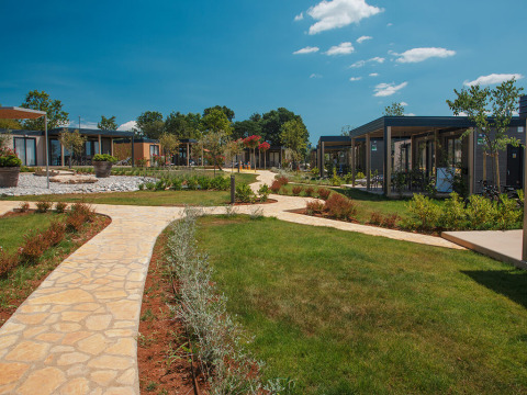 Sti og græsplæne mellem moderne chalets i Mediterranean Garden Home ved Valamar Camping Lanterna, Kroatien.