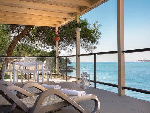 Terrasse du chalet Marbello Home avec vue sur la mer, transats, table à manger et toit en pergola.