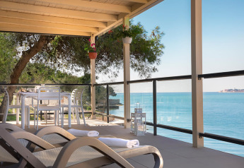 Afslappet terrasse på Marbello Home chalet med havudsigt, solsenge og spisebord under pergola.