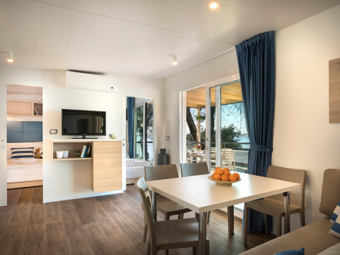 Espace séjour moderne au chalet Marbello Home avec table à manger, canapé et vue sur la terrasse et la mer.