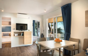 Modernes Wohnzimmer im Marbello Home Chalet mit Esstisch, Sofa und Blick auf Terrasse und Meer.