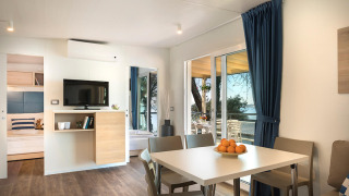 Modernes Wohnzimmer im Marbello Home Chalet mit Esstisch, Sofa und Blick auf Terrasse und Meer.