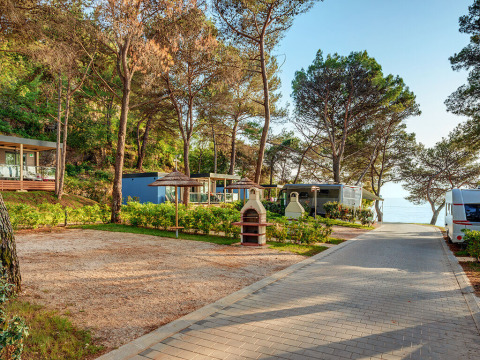 Chalets et caravanes à l'ombre des arbres à Marbello Home, avec vue sur la mer et barbecue extérieur aménagé.