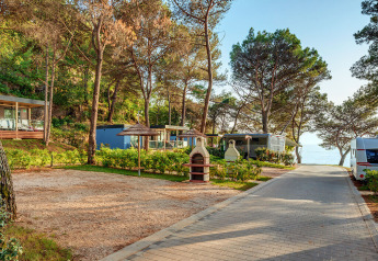 Chalets en mobilhomes onder bomen bij Marbello Home, met zeezicht en buitenfaciliteiten aan een wandelpad.