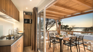 Gemütliche Happy Dog Home-Lodge mit offener Küche, Terrasse, Seeblick und gedecktem Esstisch.