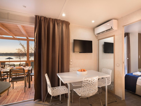 Moderne glampingaccommodatie met eethoek, flatscreen-tv, airconditioning en terras met uitzicht op het meer.
