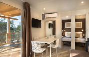 Modernes Lodge-Interior mit Esstisch, TV und Terrasse im Happy Dog Home im Valamar Camping Lanterna, Kroatien.