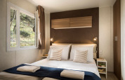 Modernes Schlafzimmer im Happy Dog Home Glamping mit Doppelbett, Fenster, Holzschränken und Leselampen.