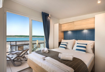 Slaapkamer in Marbello Home chalet bij Valamar Camping Lanterna in Kroatië met zeezicht vanaf het terras.