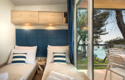 Modernes Chalet-Zimmer mit zwei Einzelbetten, blauen Akzenten und Meerblick im Valamar Camping Lanterna, Kroatien.