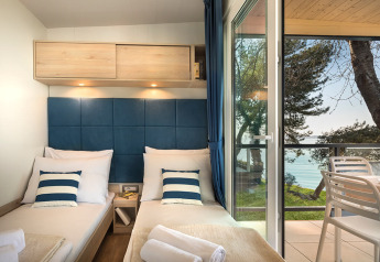Moderne chaletkamer met twee eenpersoonsbedden, blauwe tinten en zeezicht bij Valamar Camping Lanterna Kroatië.