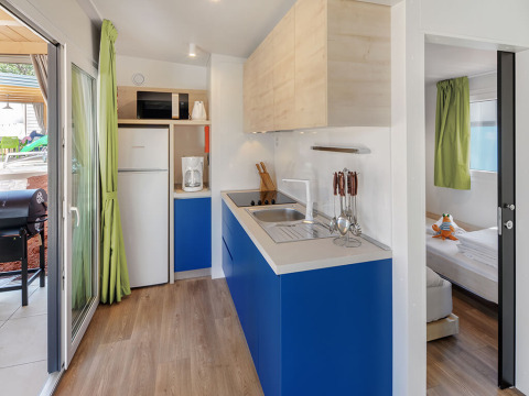 Modern chalet kitchen at Maro Home, Valamar Camping Lanterna, Croatia, featuring blue cabinets and appliances.