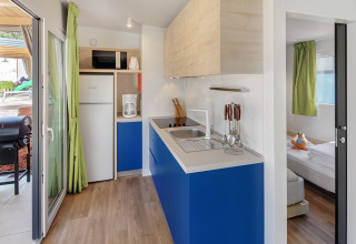 Modern chalet kitchen at Maro Home, Valamar Camping Lanterna, Croatia, featuring blue cabinets and appliances.