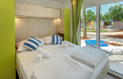 Modernes Schlafzimmer im Maro Home Chalet auf dem Valamar Camping Lanterna in Kroatien mit Terrassenausblick.