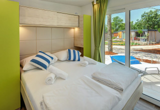 Modern bedroom inside Maro Home chalet at Valamar Camping Lanterna in Croatia, featuring terrace and garden view.