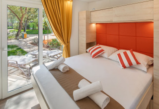 Chalet moderne avec lit double, coussins rouges et terrasse chez Maro Home, Valamar Camping Lanterna, Croatie.