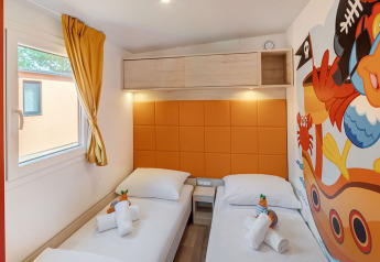 Børneværelse i Maro Home, Valamar Camping Lanterna, Kroatien med to enkeltsenge og farverigt piratmaleri.