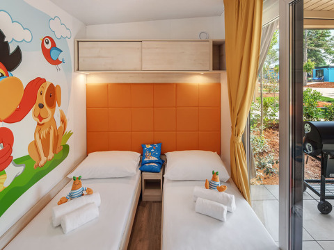 Chambre enfantine à Maro Home, Valamar Camping Lanterna en Croatie, lits jumeaux, fresque murale colorée et vue patio.