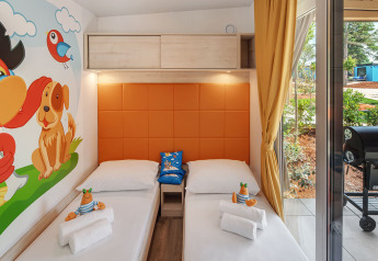 Børneværelse i Maro Home på Valamar Camping Lanterna i Kroatien med to enkeltsenge, farverig vægkunst og udsigt udendørs.