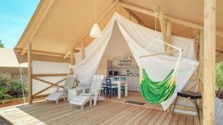 Maro Premium Glamping-Zelt mit Holzterrasse, Hängesessel und bequemen Stühlen vor einer offenen Zeltfront.
