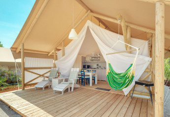 Maro Premium Glamping Tent met houten terras, hangstoel en loungezetels onder een open tentdoek.