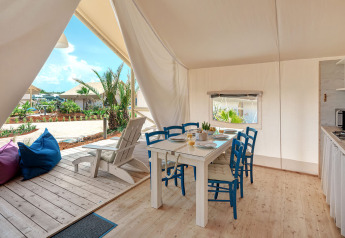Binnenzicht van de Maro Premium Glamping Tent met eettafel en terras bij Valamar Camping Lanterna, Kroatië.