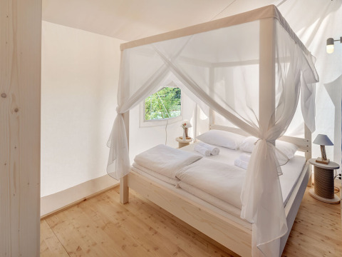Lichte en elegante slaapkamer met hemelbed in Maro Premium Glamping Tent op Valamar Camping Lanterna, Kroatië.