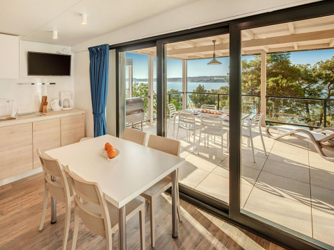 Intérieur de la Marbello Suite au Valamar Camping Lanterna, coin repas, terrasse et vue sur la mer.
