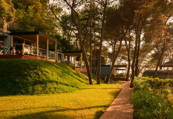Marbello Suite-hytter i Valamar Camping Lanterna, Kroatien, omgivet af træer og sollys på en sti.