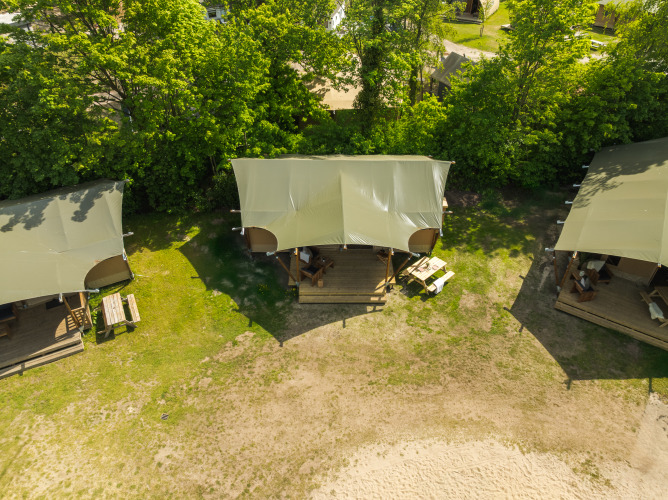 Vista aérea de tienda safari con baño en Holiday Park Mölke, Países Bajos, rodeada de árboles y naturaleza.