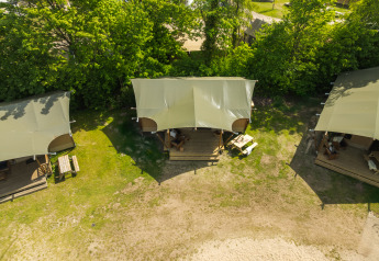 Vista aérea de tienda safari con baño en Holiday Park Mölke, Países Bajos, rodeada de árboles y naturaleza.