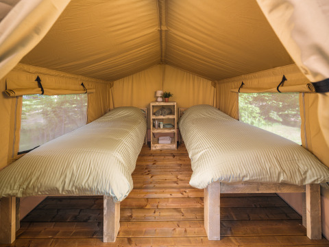 Binnenzicht van een safaritent met twee eenpersoonsbedden op houten vloer bij Holiday Park Mölke, Nederland.