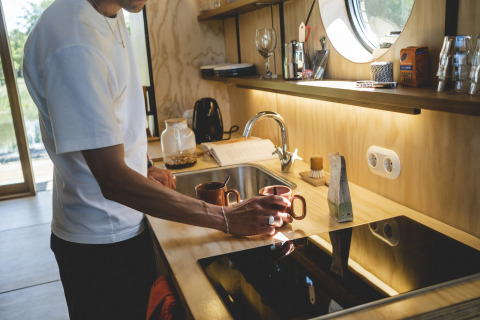 Hombre prepara café en cocina moderna en Wrap house con sauna y bañera en Resort de Parel, Países Bajos.