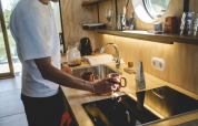 Man maakt koffie in moderne keuken in Wrap house met sauna en bad bij Resort de Parel, Nederland.